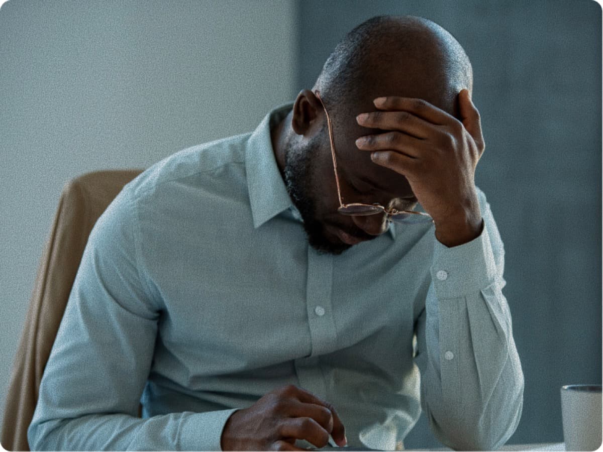 Stressed man with head in hands representing financial risk